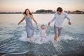 Happy young family having fun running on water at the beach Royalty Free Stock Photo