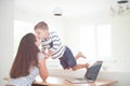 Happy young family of little boy kissing his mother woman on table with laptop in bright room at home during self isolation Royalty Free Stock Photo