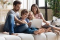 Happy family with small children watching video on laptop