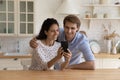 Happy young family looking at smartphone screen, sitting in kitchen Royalty Free Stock Photo