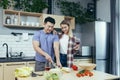 Happy young family, man and woman, cooking together, Asian cuts vegetables, date at home, romantic evening Royalty Free Stock Photo