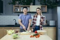 Happy young family, man and woman, cooking together, Asian cuts vegetables, date at home, romantic evening Royalty Free Stock Photo