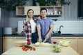 Happy young family, man and woman, cooking together, Asian cuts vegetables, date at home, romantic evening Royalty Free Stock Photo