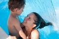 Happy young family of mother woman and little wet child in swimming pool under waterfall jet turquoise spa hydrotherapy water Royalty Free Stock Photo