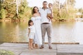 Happy young family near lake, pond on summer on countryside. Mother, father and two child daughter smiling and having Royalty Free Stock Photo