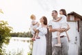 Happy young family near lake, pond on summer on countryside. Mother, father and two child daughter smiling and having Royalty Free Stock Photo