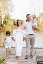 Happy young family near lake, pond on summer on countryside. Mother, father and two child daughter smiling and having Royalty Free Stock Photo