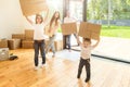 Happy young family, parents daughter and son, unpacking boxes and moving into a new home. funny kids run in with boxes Royalty Free Stock Photo