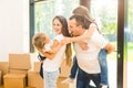 Happy young family, parents daughter and son, unpacking boxes and moving into a new home. funny kids run in with boxes Royalty Free Stock Photo