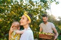 The happy young family during picking apples in a garden outdoors Royalty Free Stock Photo