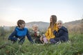 Happy young family on picnic communicate and smiling. Three siblings with mother resting on the nature Royalty Free Stock Photo