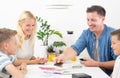 Happy young family playing card game at dining table at bright modern home. Royalty Free Stock Photo