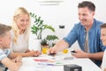 Happy young family playing card game at dining table at bright modern home. Royalty Free Stock Photo