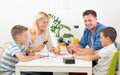 Happy young family playing card game at dining table at bright modern home. Royalty Free Stock Photo