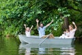 happy young family with raised hands riding boat on lake