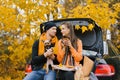 A happy young family is relaxing after a day spent outdoors in the autumn forest. A couple in love is sitting in the trunk of a Royalty Free Stock Photo