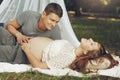 Happy young family, relazing in sunny park, happy husband holding pregnant wife belly, while looking at her. gentle moments of p Royalty Free Stock Photo