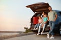 Happy young family sitting in car trunk Royalty Free Stock Photo
