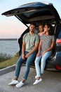 Young family sitting in car trunk on riverside Royalty Free Stock Photo