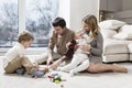 Happy young family with small children are resting in the living room. The pleasure of spending time together Royalty Free Stock Photo