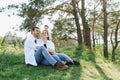 Happy young family spending time outdoor on a summer day have fun at beautiful park in nature while sitting on the green grass. Royalty Free Stock Photo