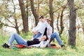 Happy young family spending time outdoor on a summer day have fun at beautiful park in nature while sitting on the green grass. Royalty Free Stock Photo