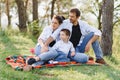 Happy young family spending time outdoor on a summer day have fun at beautiful park in nature while sitting on the green grass. Royalty Free Stock Photo