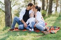 Happy young family spending time outdoor on a summer day have fun at beautiful park in nature while sitting on the green grass. Royalty Free Stock Photo