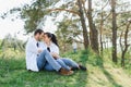 Happy young family spending time outdoor on a summer day have fun at beautiful park in nature while sitting on the green grass. Royalty Free Stock Photo