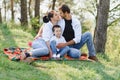 Happy young family spending time outdoor on a summer day have fun at beautiful park in nature while sitting on the green grass. Royalty Free Stock Photo