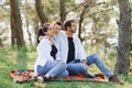 Happy young family spending time outdoor on a summer day have fun at beautiful park in nature while sitting on the green grass. Royalty Free Stock Photo