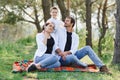 Happy young family spending time outdoor on a summer day have fun at beautiful park in nature while sitting on the green grass. Royalty Free Stock Photo