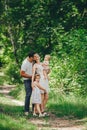 Happy young family spending time together in green nature park. Mother and father kissing baby daughters Royalty Free Stock Photo