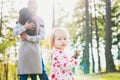 Happy young family taking a walk in a park. Toddler girl daughter looking at camera in the foreground. Royalty Free Stock Photo