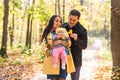 Happy young family with their daughter spending time outdoor in the autumn park. Royalty Free Stock Photo