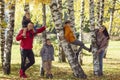 Happy young family with three children in the park. Sons sit on trees in a birch grove. Love and tenderness Royalty Free Stock Photo