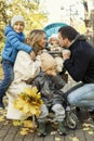 Happy young family with three small children in a beautiful autumn park are walking and hugging. Love, tenderness and Royalty Free Stock Photo
