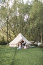 Happy young family with two children spending time together outside in nature, sitting near the big tent and holding Royalty Free Stock Photo