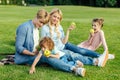 happy young family with two kids eating green apples while resting on grass Royalty Free Stock Photo