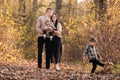 Happy young family with two little children walking and having fun in autumn park on sunny day Royalty Free Stock Photo