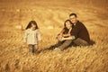Happy young family with two year old baby girl sitting on the ground in harvested field Royalty Free Stock Photo