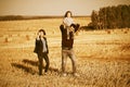 Happy young family with two year old baby girl walking in harvested field Royalty Free Stock Photo