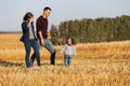 Happy young family with two year old girl walking in harvested field