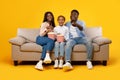 Happy young family watching television with popcorn sitting on sofa Royalty Free Stock Photo