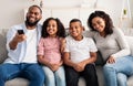 Happy young family watching television sitting on sofa Royalty Free Stock Photo