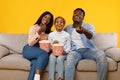 Happy young family watching television sitting on sofa Royalty Free Stock Photo