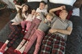 Happy young family wear pajamas and lie on large bed. Mother father and three children. Top view. Christmas or New Year Morning. Royalty Free Stock Photo