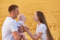 Happy young family in wheat field playing with small child. Young mom dad and child outdoors Royalty Free Stock Photo