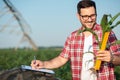 Happy young farmer or agronomist measuring young corn plant stem size with a ruler, writing data to a questionnaire Royalty Free Stock Photo