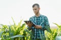 Happy young farmer or agronomist using tablet in corn field. Irrigation system in the background. Organic farming and food Royalty Free Stock Photo